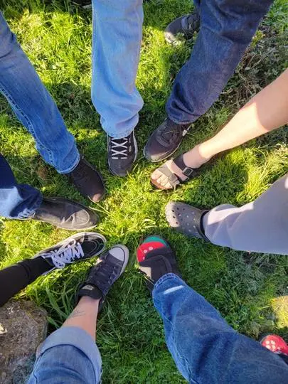 A group of people standing in the grass with their feet