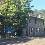 A building with trees in the background and a street sign.
