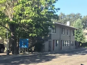 A building with trees in the background and a street sign.